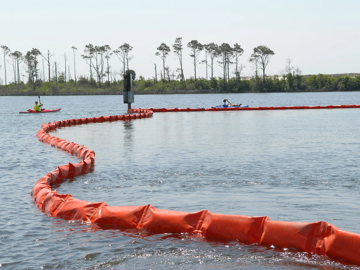 An orange floating containment boom curving across open water